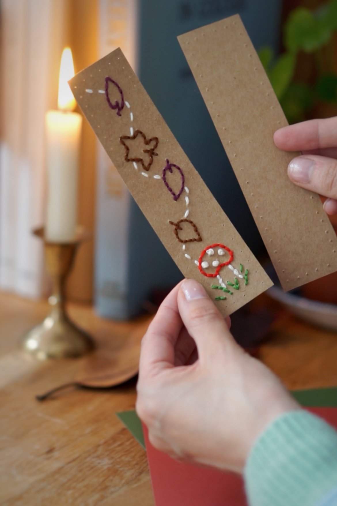 Hands hold the embroidered front piece of the bookmark and the plain back piece.