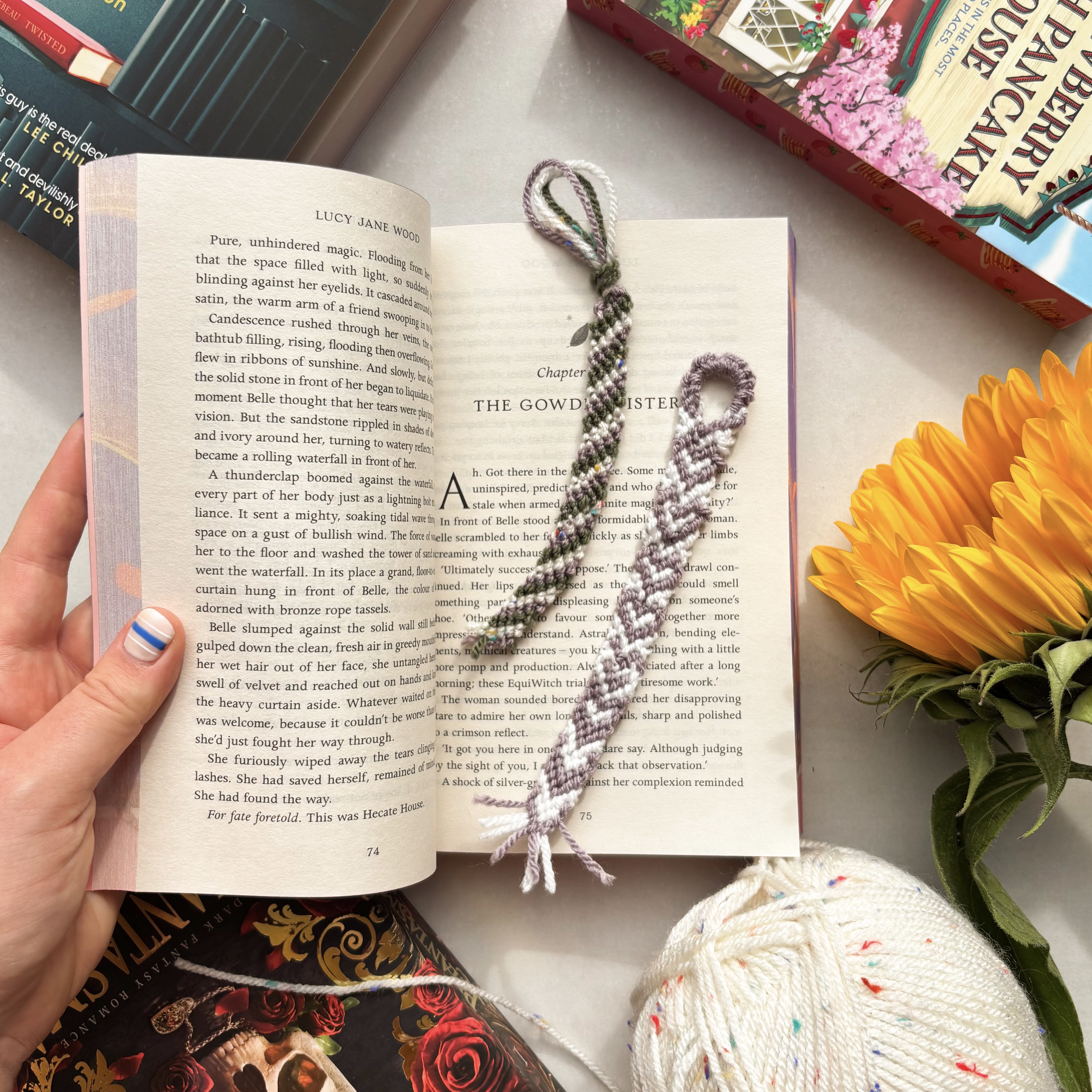 Finished knotted friendship bracelet bookmarks on an open page of a novel with a sunflower.