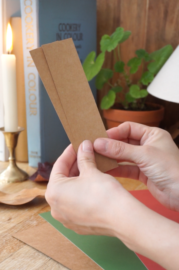 Hands holding two pieces of rectangular kraft card.
