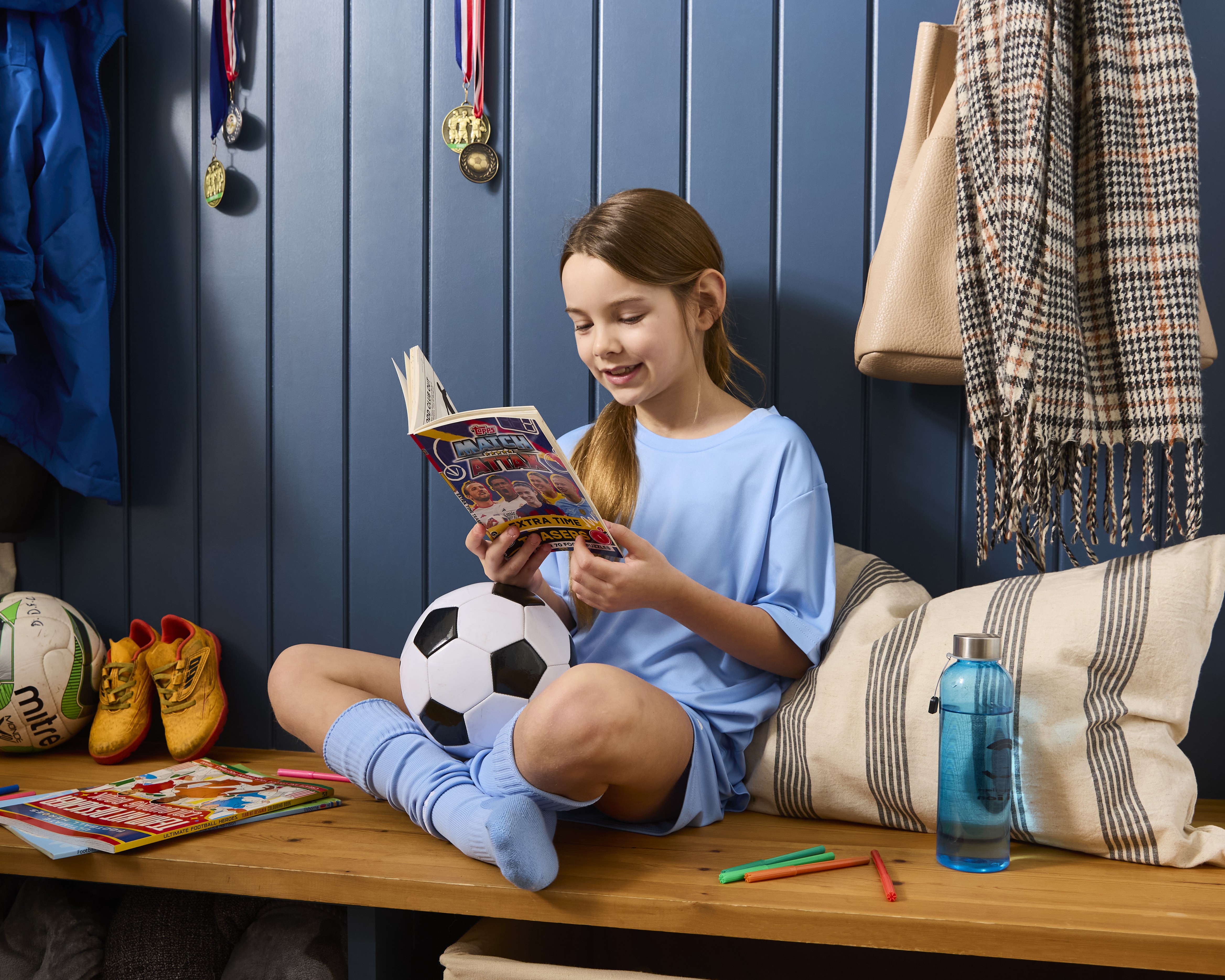 Girl reading a football book on a bench after football.
