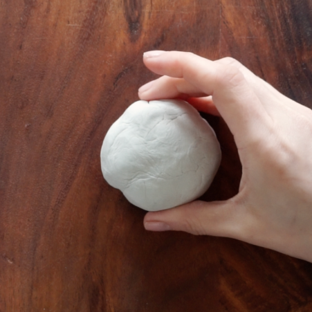 Hand holding air dry clay in a ball.