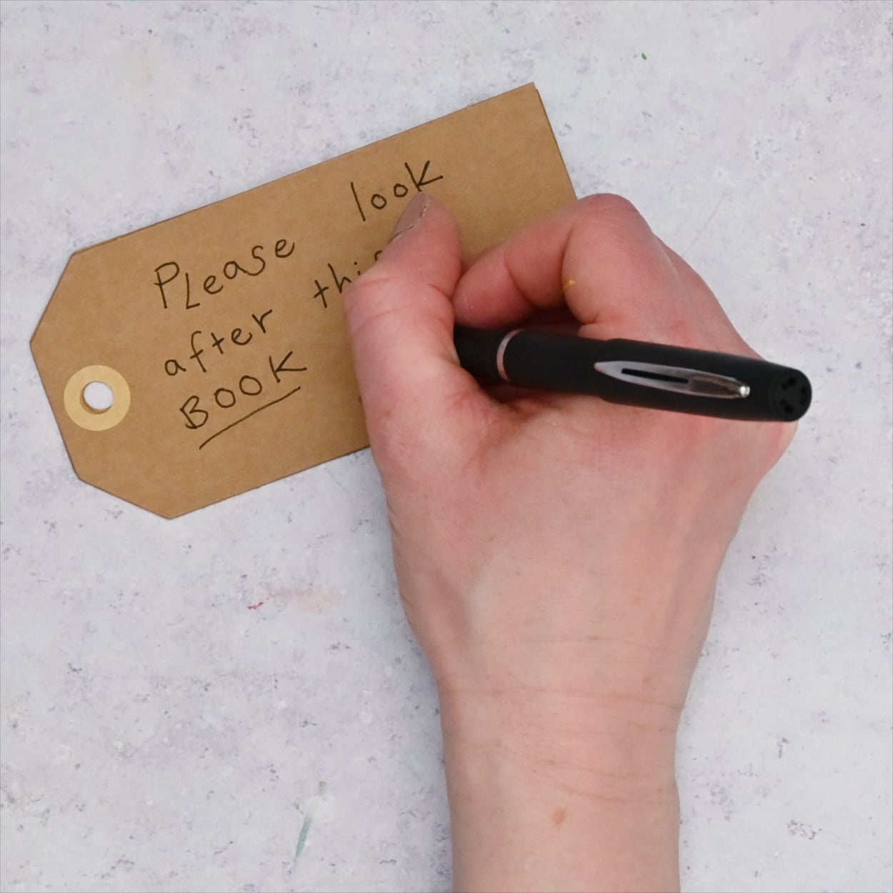 Black pen writing a message on the luggage tag.