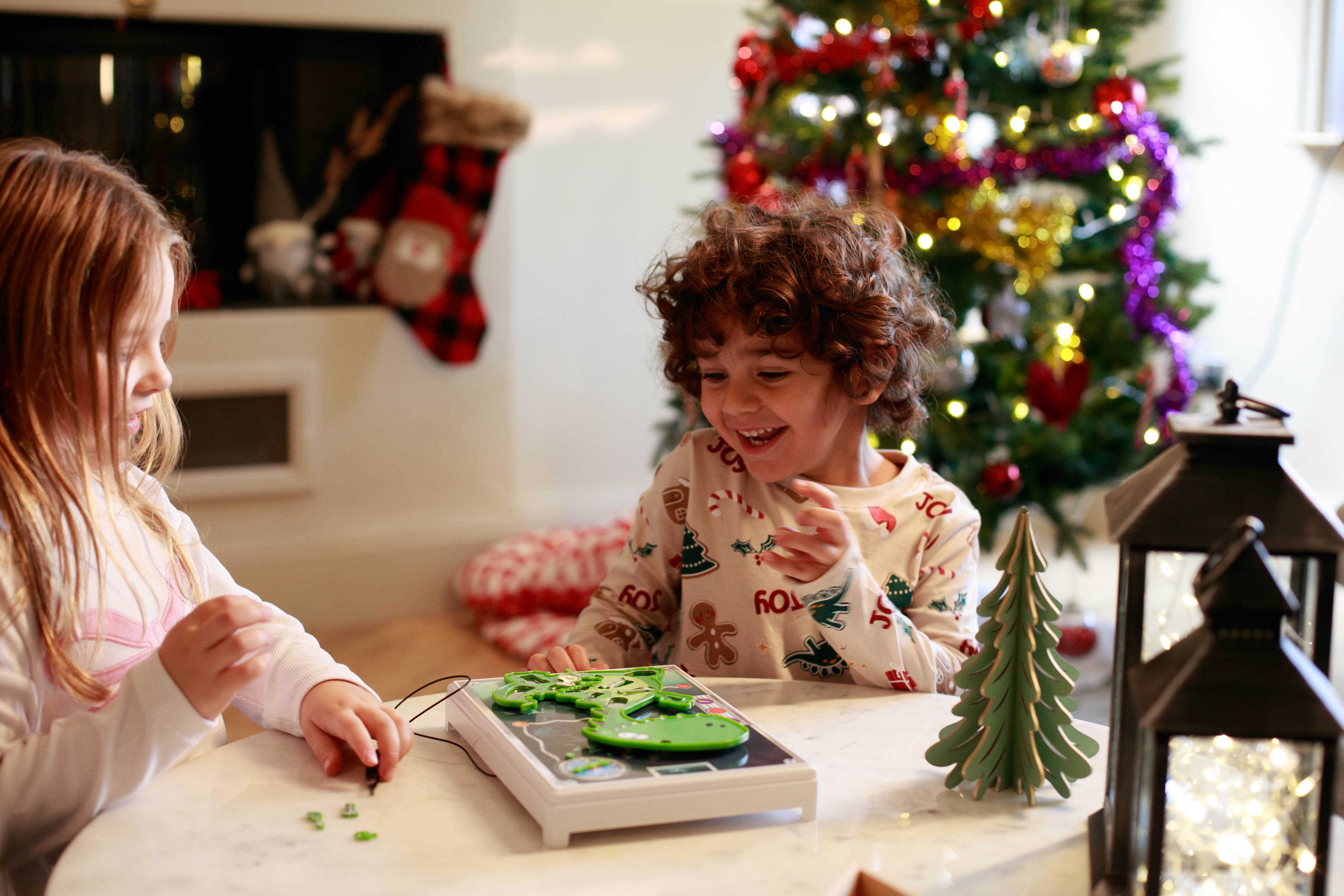 Two children playing Dino Operation. The young boy is beaming at the game.