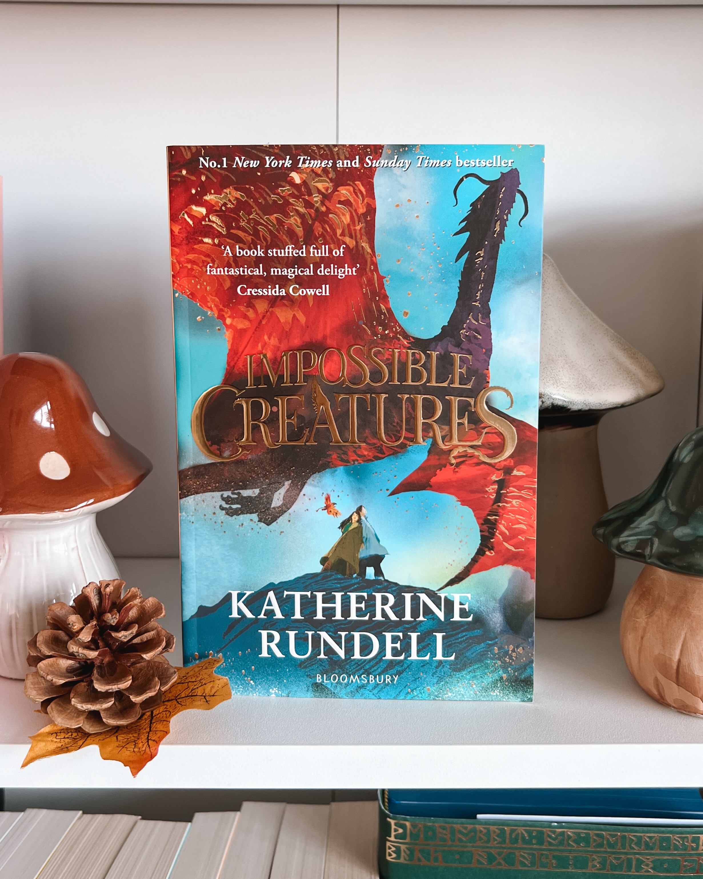 Impossible Creatures book stands on a bookshelf with mushroom decor either side