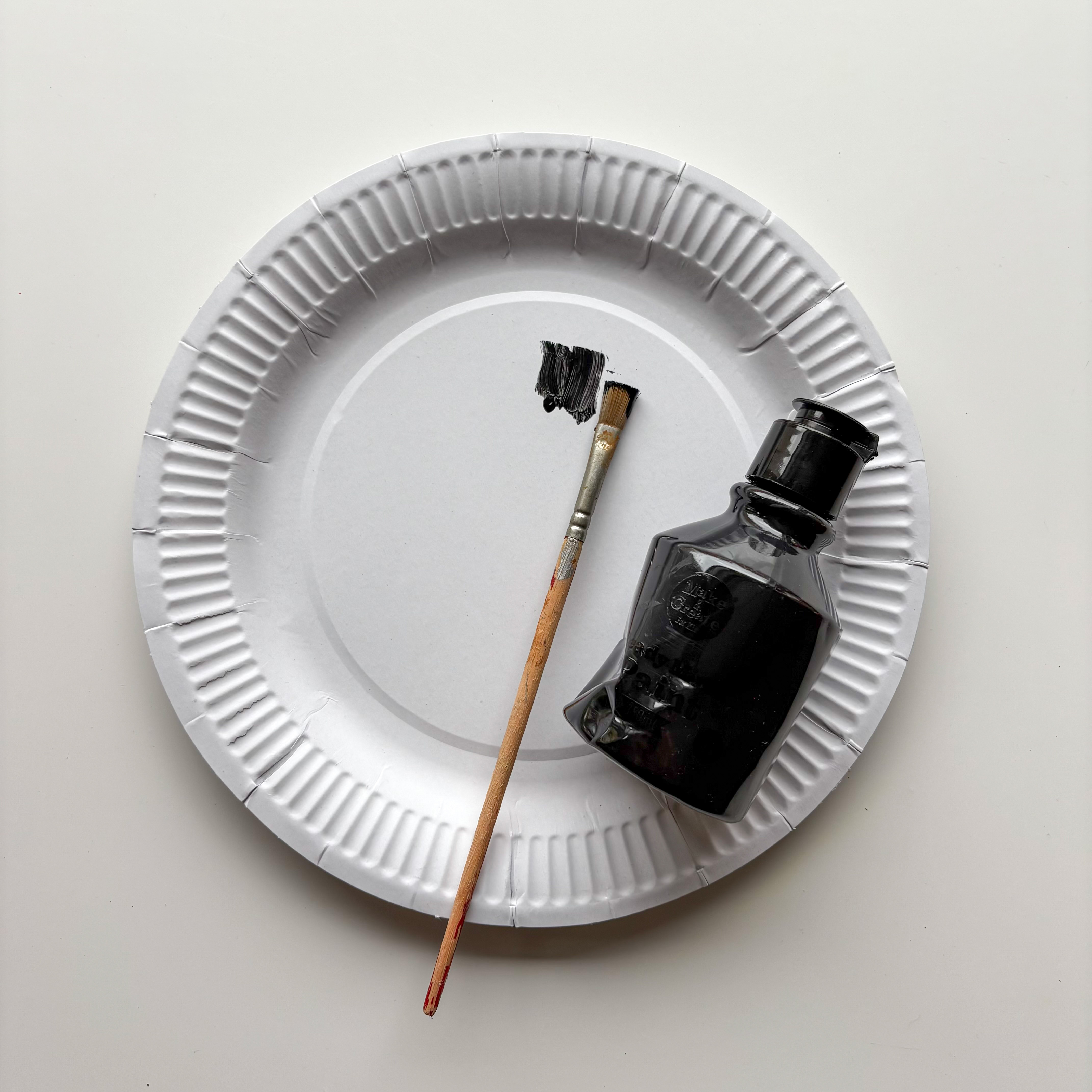 Paint the top of your paper plate black. Let it dry, then add a second coat so it’s nice and dark.