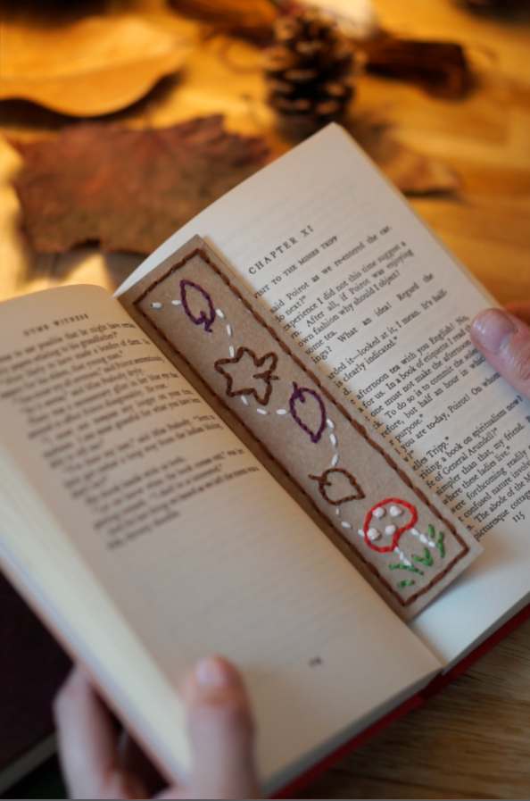 Autumn Embroidered Bookmark Complete The completed autumn embroidered bookmark rests in the middle of an open book.