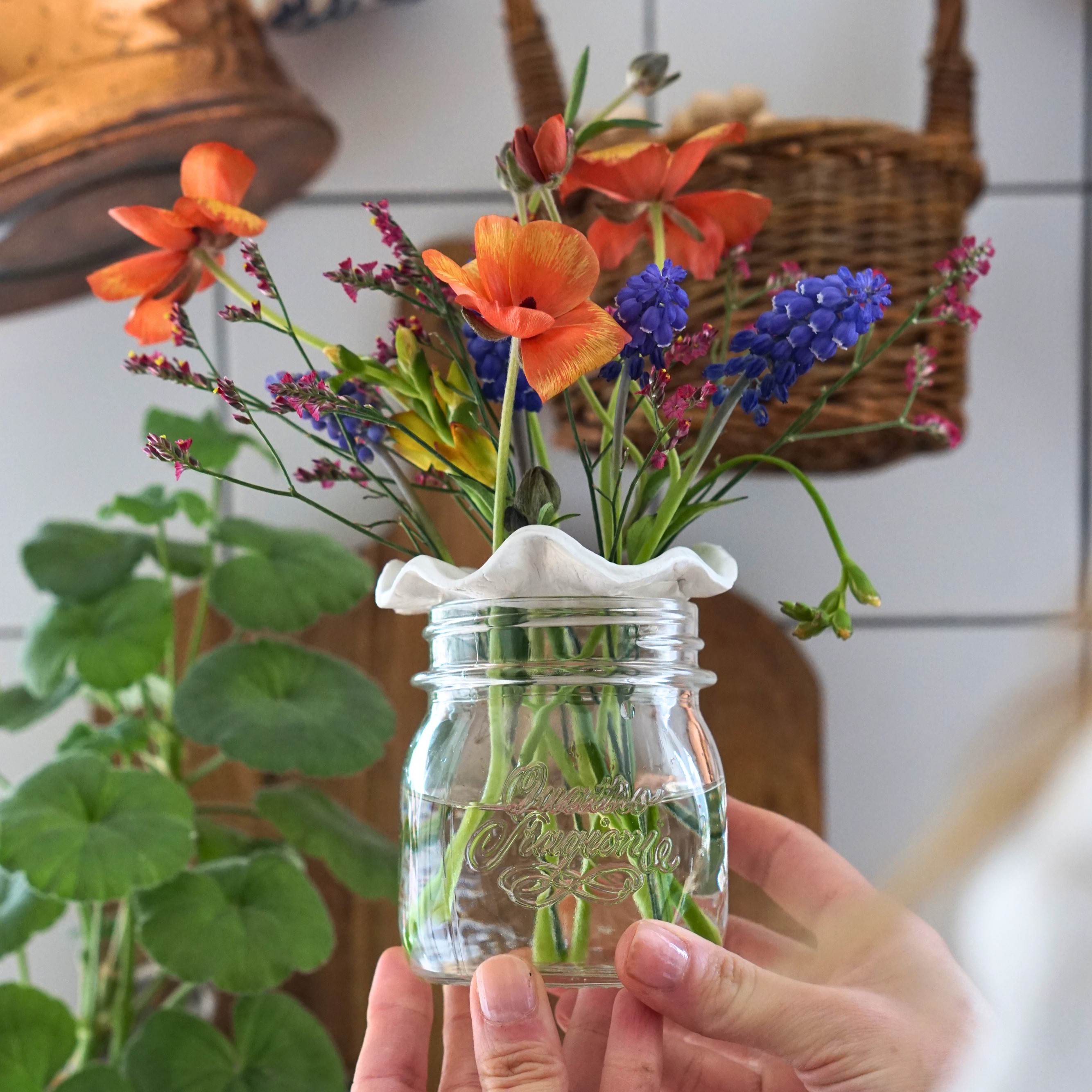 Finished flower frog sat on a jar with some flowers poked throug the holes.